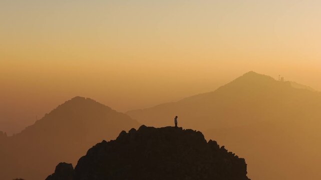 4K drone footage of a peaceful sunrise over Himalayan mountains with a boy standing on a cliff.