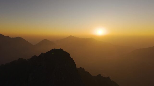 4K drone footage of a lone traveler standing on rocky terrain during sunrise in Uttarakhand, India.