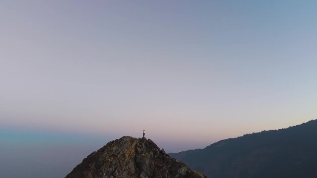 4K aerial panoramic drone footage of a traveler standing on a mountain cliff above the Himalayas in India.