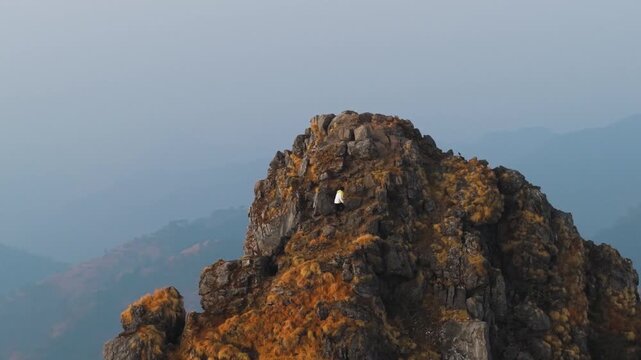 4K cinematic aerial footage of a boy climbing a dramatic mountain ridge with vibrant morning skies in the Himalayas.