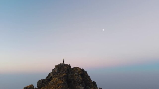 4K cinematic drone footage of a boy standing on a dramatic mountain peak with layered Himalayan scenery behind him.