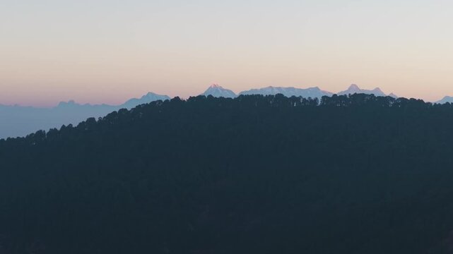 4K aerial drone shot of snow-covered Himalayan peaks including Trishul and Nanda Devi during sunrise in Uttarakhand, India.