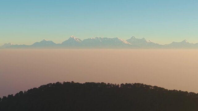 4K cinematic sunrise drone view of snow-covered Himalayan peaks with vibrant morning skies in Uttarakhand.