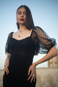 Beautiful and sensual young woman in a dress on a building rooftop in the golden hour