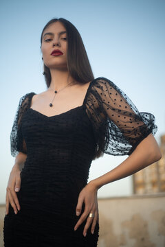 Beautiful and sensual young woman in a dress on a building rooftop in the golden hour