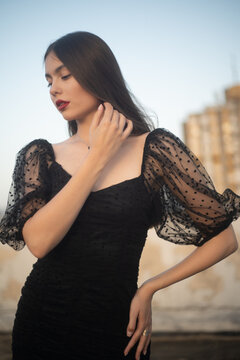 Beautiful and sensual young woman in a dress on a building rooftop in the golden hour