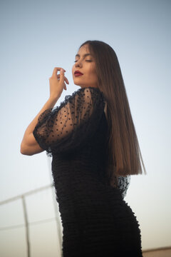 Beautiful and sensual young woman in a dress on a building rooftop in the golden hour
