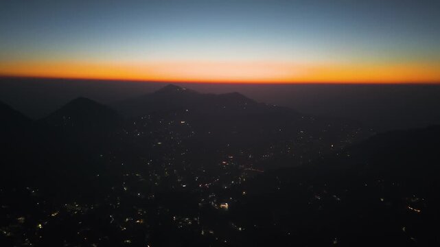 4K drone shot capturing the beautiful skyline of Nainital at sunrise with city lights and Himalayan backdrop in India.