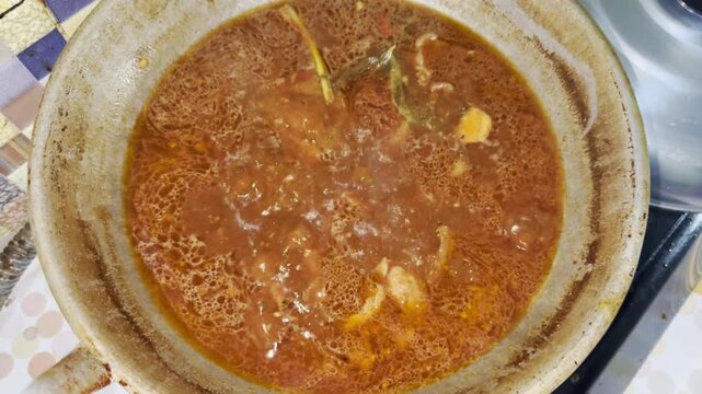 Boiling beef in wok during traditional Indonesian rendang cooking process, authentic Padang cuisine preparation