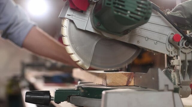 A person is using a power saw to cut a piece of wood