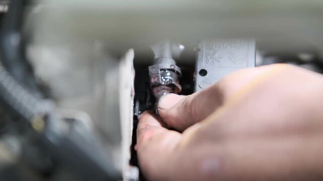 Close Up of Mechanic Hand Plugging a Pink Antifreeze Coolant Leak inside a Car Engine Bay