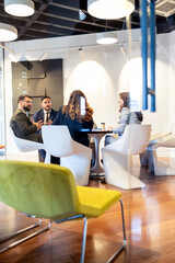Naklejka na ściany i meble Business team collaborating in modern office lounge, discussing strategies during a corporate meeting, having a professional discussion