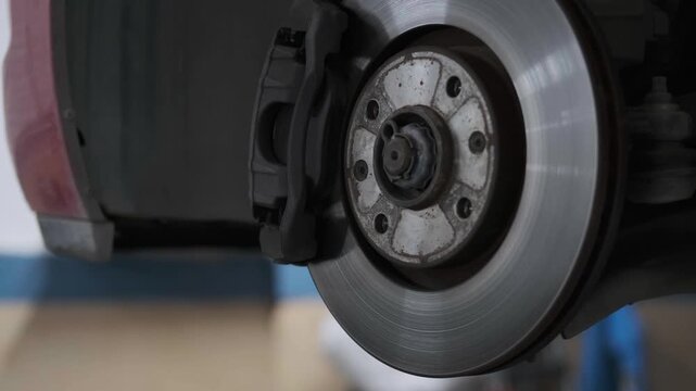 Close Up of Mechanic Hand Cleaning and Wiping a Car Brake Disc Rotor with a Rag in an Auto Repair Shop