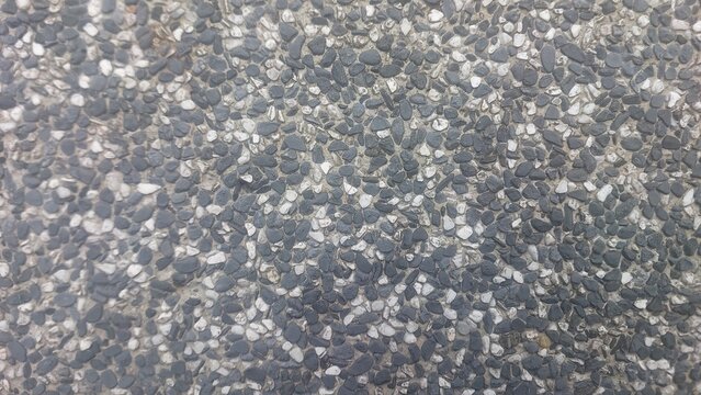Close up of pebble finish concrete surface showing embedded dark and light stones in textured pattern