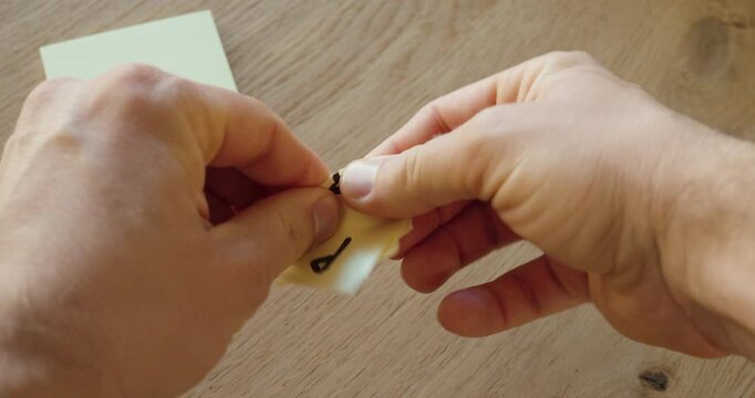 Close-up of hands tearing up a paper note with a handwritten PIN code, symbolizing IT security risk, data protection, privacy awareness, and safe handling of confidential information.