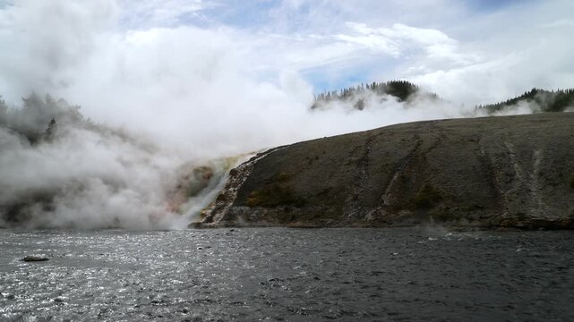 Grand Prismatic Spring Firehole River largest hot springs steaming pool Mid Geyser Basin Wyoming USA Yellowstone National Park nature landscape riverbank Midway Boardwalk sunny blue sky morning pan