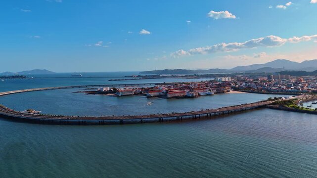 Aerial View of Casco Viejo Panama City Curved Causeway. A curved coastal highway encircles Casco Viejo peninsula with red-roofed colonial buildings below.