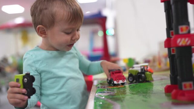 Young child playing with toy train. Boy, plays, railroad, toys carriages, train, son. A train with carriages and a boy playing with it. The photo is of a child playing with a lifestyle toy train.