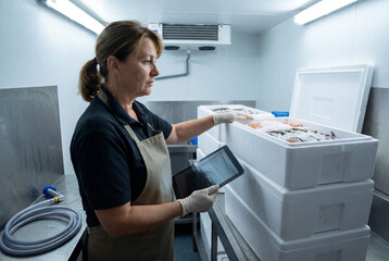 Obraz premium Woman Managing Seafood Inventory in Cold Storage