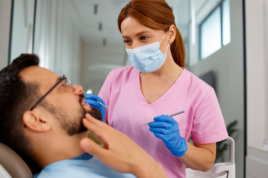 Female dentist examining male patient during dental consultation