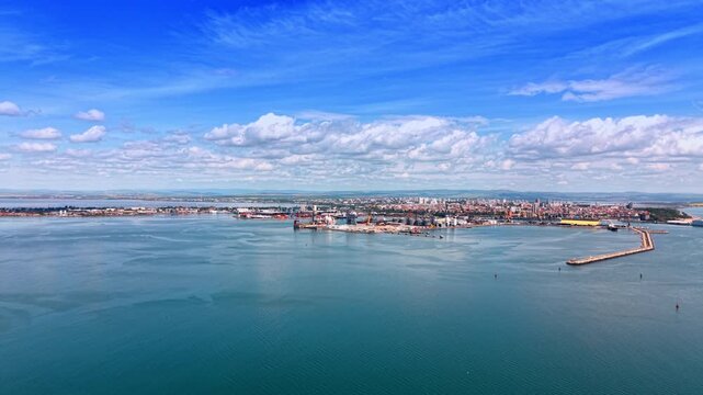 Wide Aerial Panorama Port City Black Sea Breakwater. A wide aerial panorama shows a Black Sea port city with industrial quays and a curved breakwater.