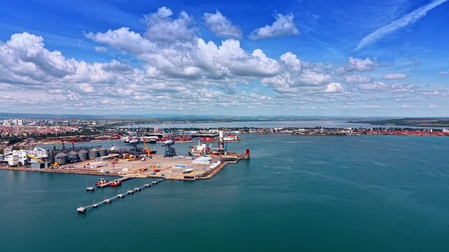 Port Burgas Ships Silos Cranes Lagoon. A wide aerial view captures the full Burgas port with ships, grain silos, cranes and inner lagoon.