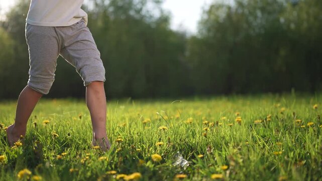 Child running in field. Child runs on the grass in a park. A kid is running in the park. Lifestyle a kid sprinting across a meadow.