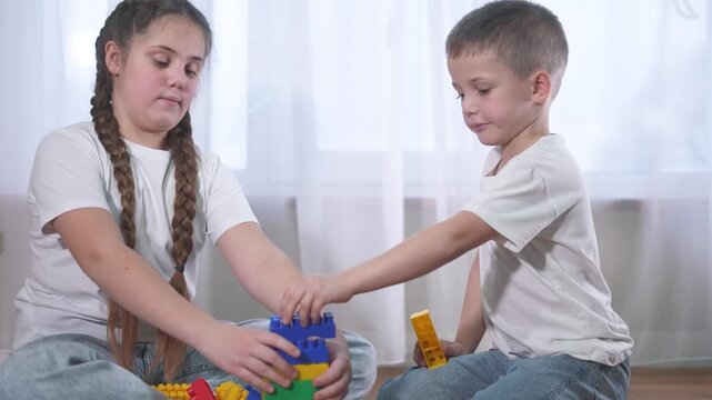 Two children playing with blocks. A group of lifestyle children are assembling a construction. A group of kids play with toys. Two kids stacking blocks.