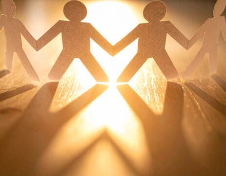 Paper human chain showcasing unity and support with a warm glowing light.