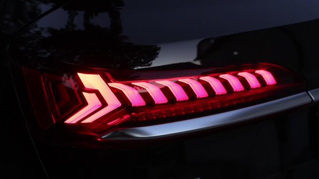 Rear LED lights closeup of electric SUV, stylish exterior design of car. Headlight, taillight, car, brake, indicator, led, light. Close up detail on one of the LED red taillight modern crossover car