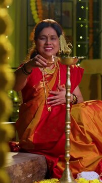 Lighting traditional samai with diya, Indian young girl in ethnic wear and senior mother joyfully celebrating Hindu festival Diwali in evening at home with festive decor and glowing diya illumination