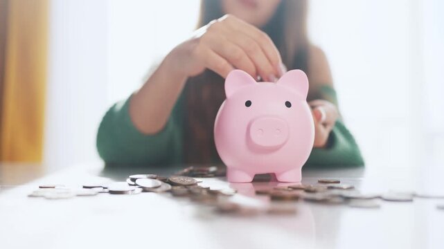 The girl puts coins into the piggy bank. the concept of saving money is saving. man puts a piggy in his hand and puts money in a bank. lifestyle a girl puts coins in her hand in a bank.