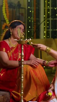 Lighting samai diya indoors during Diwali, Indian family of four including senior mother in saree, father, young girl, and husband smiling together celebrating Hindu festival with joy and tradition