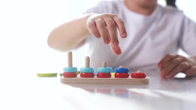 Child plays with toy r rings pyramid on table in lifestyle kindergarten. Fun childhood leisure. concept. The child masters fine motor. skills. Child masters fine motor skills, educational game.