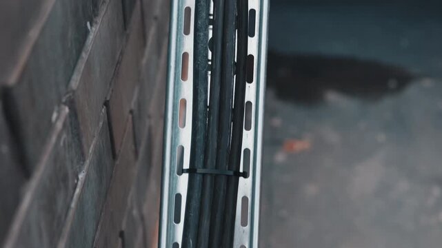 Electrical cables mounted in metal cable tray on building wall
