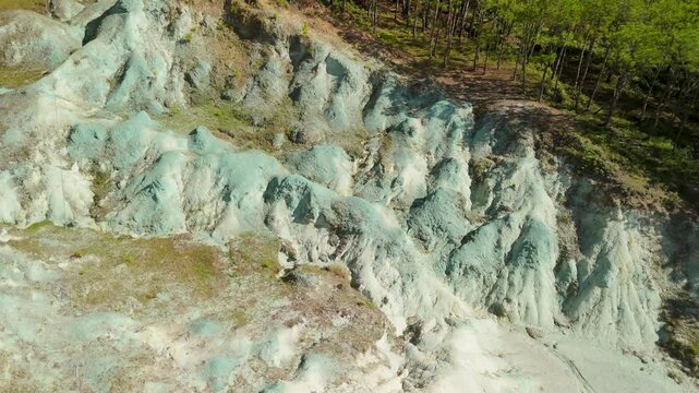 Close-up aerial reveals intricate ridged texture of Sagada Blue Soil Hills white clay formation glowing in sunlight beside pine forest in Mountain Province Philippines