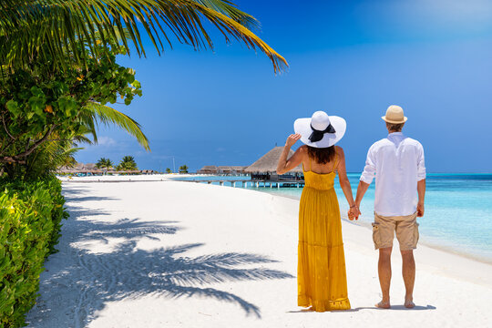 Rear view of a beautiful couple standing on a tropical beach in the Maldives islands during their vacation time