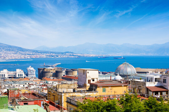 Panoramic view of Naples, Italy with Castel Nuovo and Galleria Umberto I under clear sky, overlooking Bay of Naples with ships and cruise liner