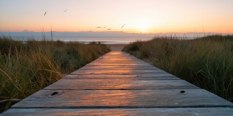 Obraz premium The Boardwalk Leading Through Dune Grasses To A Tranquil Sunset Beach