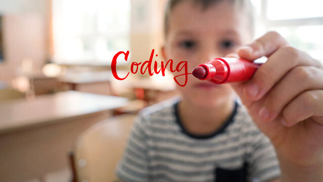Young child drawing with red marker pen on glass, close-up of handwriting coding text in classroom, early education learning programming skills at school, technology creativity concept