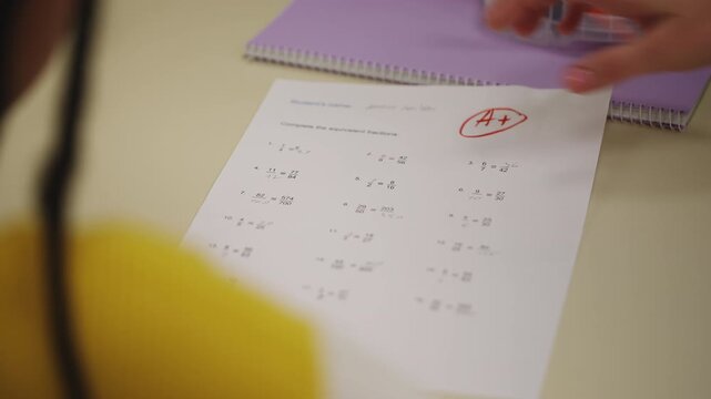 Teacher handing out math test paper to girl celebrating excellent grade