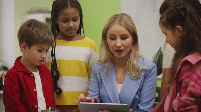 Teacher and pupils playing educational game on tablet during school lesson