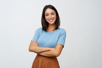 Obraz premium The woman smiling confidently with crossed arms in casual outfit on neutral background