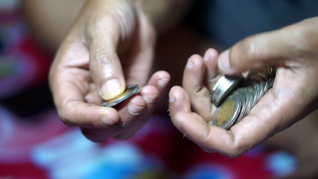 A man's hand is counting ancient bimetallic coins of 1000 Rupiah Indonesia for investment or past savings.