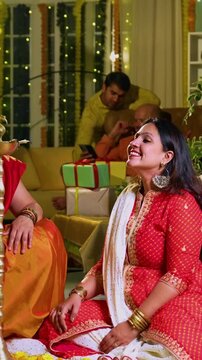 Lighting traditional samai with diya, Indian young girl in ethnic wear and senior mother joyfully celebrating Hindu festival Diwali in evening at home with festive decor and glowing diya illumination
