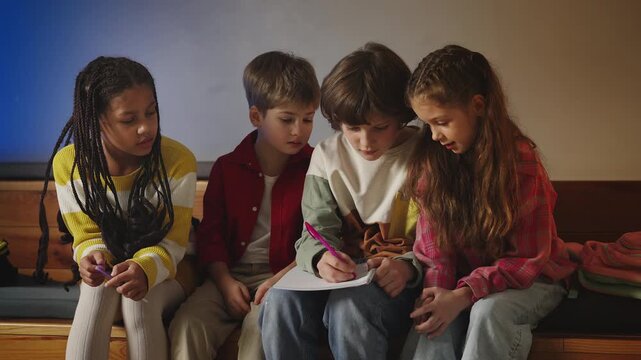 Multiracial group of pupils doing school assignment in team, problem solving