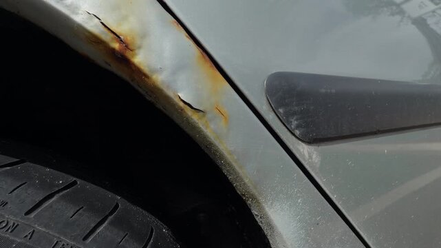 Detailed texture of vehicle wheel arch revealing corrosion and paint flaws under cloudy lighting