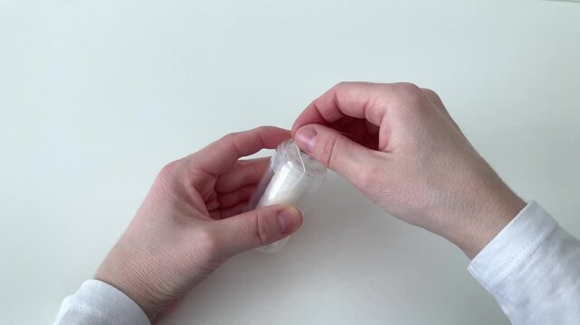 Woman takes out dental floss and tears it off in a special place. Importance of removing food debris that gets stuck between teeth and can cause discomfort and bacterial development. White background