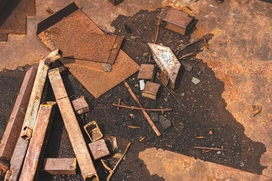 Close-up of rusted metal surfaces, including rusty nails and sheet metal in various tones of corrosion. Textured abstract industrial background with warm rusty colors.