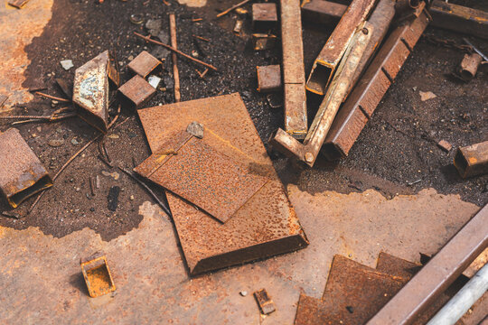 Close-up of rusted metal surfaces, including rusty nails and sheet metal in various tones of corrosion. Textured abstract industrial background with warm rusty colors.